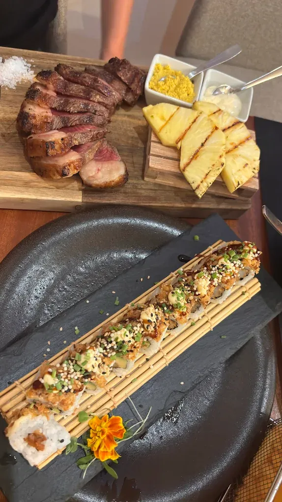Picanha grelhada e roll de sushi na mesma mesa